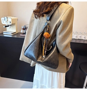 Detail of black large hobo bag with soft leather texture and stylish fur ball charm