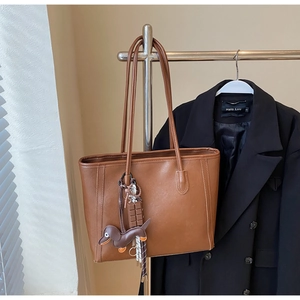 Brown faux leather tote bag with dachshund and chocolate charms on a metal display rack
