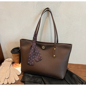 Detailed view of brown lychee texture tote bag with DA logo and polka dot silk scarf