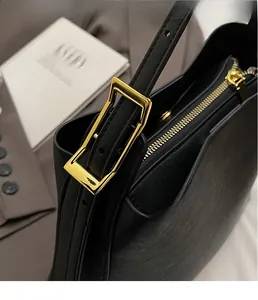 Gros plan détaillé sur la boucle dorée et la texture en cuir fin du sac seau noir