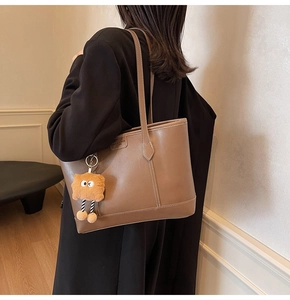 Détail du sac cabas marron vintage avec coutures blanches et charm biscuit en peluche