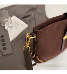 Close-up of premium brown suede shoulder bag with polished gold buckles and rivets