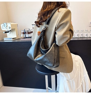 Model wearing dark grey vintage hobo bag with woven strap detail in cozy cafe setting