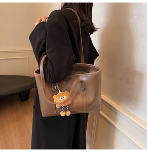 Vue détaillée du sac cabas en cuir marron avec surpiqûres blanches et breloque peluche