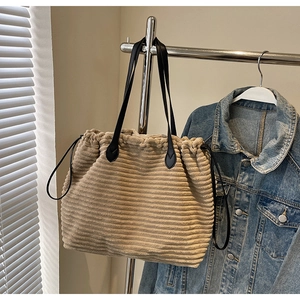 Detail of beige corduroy tote bag showing ribbed texture and black drawstring closure