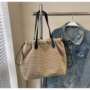 Detail of beige corduroy tote bag showing soft ribbed texture and black leather handles