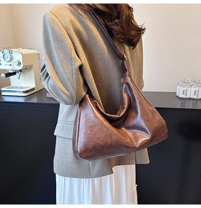 Detail of a dark brown vintage hobo bag showing supple leather texture and wide strap