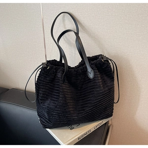 Detailed macro view of black corduroy tote bag with leather straps and drawstring texture
