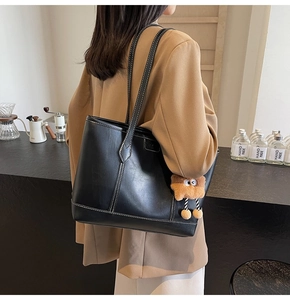 Détail du sac cabas en cuir noir avec surpiqûres blanches et breloque peluche