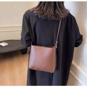 Détail d'un sac seau en cuir marron avec lettrage doré et finitions métalliques dorées