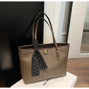 Detailed view of dark brown litchi pattern leather tote bag with polka dot silk scarf