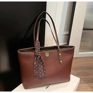 Detail of dark reddish-brown tote bag with litchi texture and polka dot scarf accessory