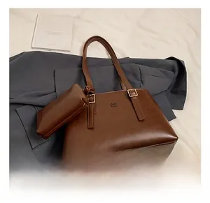 Detail showing brown faux leather tote set with shoulder straps and embossed brand logo