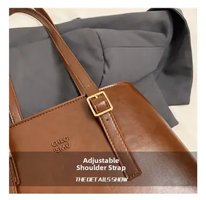 Close-up of adjustable shoulder strap with gold buckle on brown leather tote bag