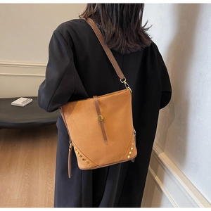 Dettaglio della grande borsa a secchiello in pelle scamosciata marrone su cappotto