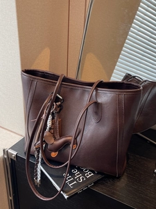 Retro brown leather tote bag with dachshund charm shown in a minimalist setting