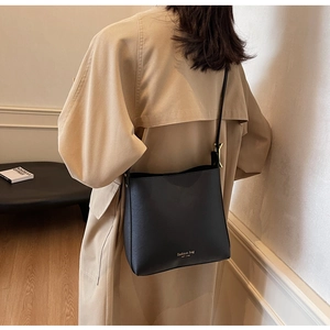 Détail du sac seau noir en similicuir avec lettrage doré et bandoulière réglable