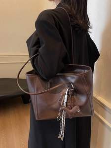 Vintage dark brown faux leather tote bag with stylish charms worn by a model