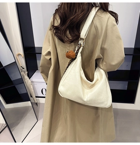 Chic hobo bag in cream leather with teddy charm and silk scarf on a trench coat