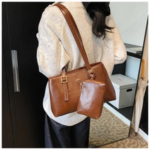 Detail of vintage brown leather tote bag with matching zipper pouch charm and shoulder strap