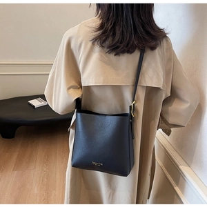 Détail du sac seau en cuir noir avec lettrage doré et bandoulière réglable pratique