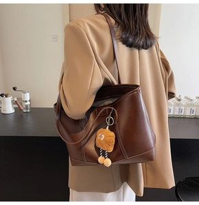 Détails du cabas en cuir marron foncé avec surpiqûres blanches et pendentif toast en peluche