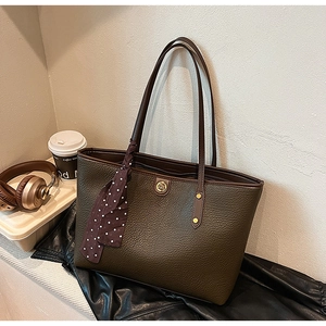 Detail of olive green pebbled leather tote bag with gold logo and polka dot silk scarf