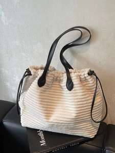 Beige corduroy tote bag with black leather straps and drawstring closure for daily commute