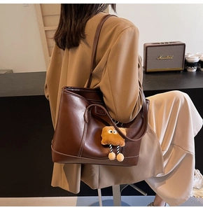 Détail d'un grand cabas marron foncé avec surpiqûres et charmant pendentif jaune