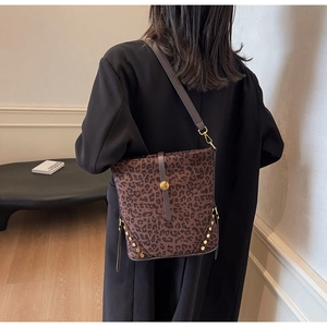 Dettaglio borsa a spalla leopardata con borchie dorate e tracolla in pelle su modella