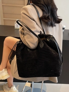 Black corduroy tote bag with leather straps and drawstring closure for daily commute