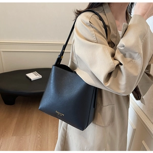Détail d'un sac seau minimaliste en cuir noir avec lettrage doré et large bandoulière