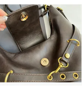 Detalle de bolso de cuero marrón oscuro con herrajes dorados vintage y cierre magnético