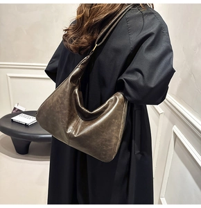 Deep brown oil wax leather hobo bag worn crossbody by a model in a minimalist setting