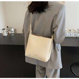 Détails du sac seau en cuir blanc crème avec grain texturé et texte imprimé chic