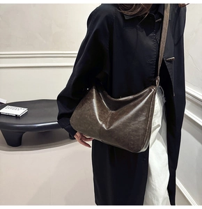 Detail of dark brown vintage faux leather hobo tote bag worn by a model in a minimal setting