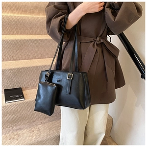Close-up of black matte leather tote bag with matching small pouch and embossed details