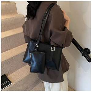 Detailed view of the black leather tote bag with matching zipper pouch and buckle strap