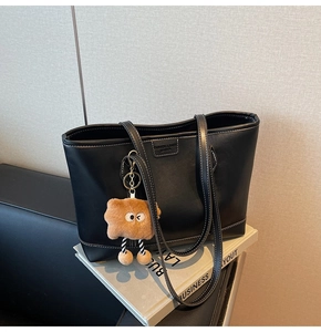 Détail du grand sac cabas noir avec surpiqûres blanches et pendentif en peluche