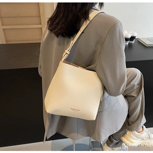 Détail d'un sac seau en cuir blanc cassé avec logo New York et bandoulière réglable