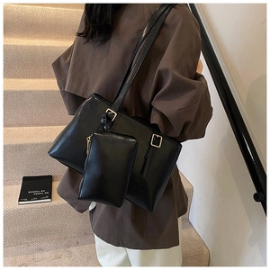Detail of minimalist black tote bag with matching pouch and gold buckles for women