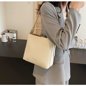 Vue détaillée du sac seau crème avec bandoulière réglable et lettrage de mode chic