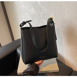 Détail d'un sac cabas noir minimaliste avec boucles dorées et texte de mode