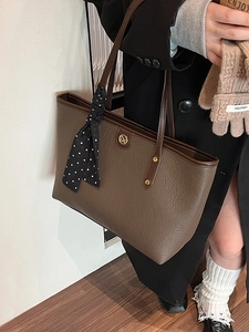 Large brown textured leather tote bag with gold logo and stylish polka dot scarf detail