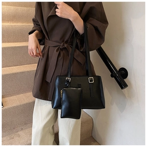 Close-up of a black minimalist tote bag with small pouch and metal buckle detail