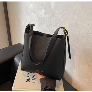 Détail du sac seau en cuir PU noir avec typographie dorée et boucles métalliques