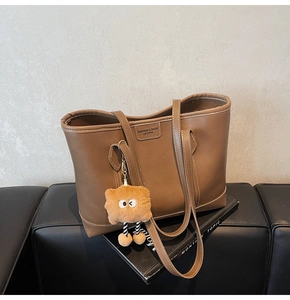 Gros plan d'un sac cabas en cuir marron avec étiquette mode et charm en peluche mignon