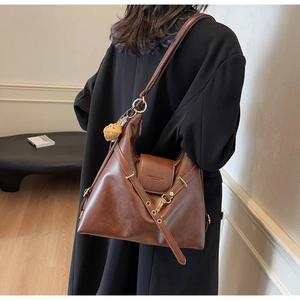 Detalle de la textura de cuero marrón oscuro y hebilla metálica del bolso para mujer