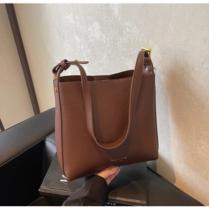 Détail de sac seau marron foncé montrant la fermeture magnétique et les ferrures dorées