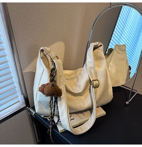 Detail of adjustable golden buckle and plush puppy charm on cream white tote bag